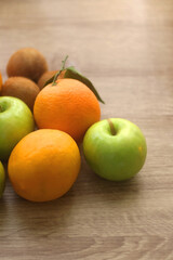 Pineapple, apples, oranges, lemons and kiwis on a wooden table. Selective focus.