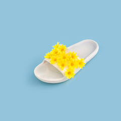 Creative summer concept with rubber slipper with yellow flowers
