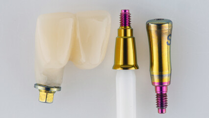 two dental crowns of the central incisors and an abutment in gold color, top view on a white background