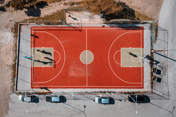 Basketball court in an urban suburb with parked cars, aerial view. The concept of district...