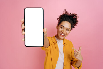Smartphone mock-up. Excited happy african american girl, holding cellphone in hand with blank white...