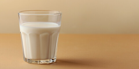 Banner. A glass of fresh milk on a beige background. Copy space
