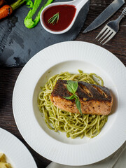 spaghetti pesto salmon on wooden table.