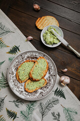 Toasted white bread toast with garlic basil butter on a vintage plate. Morning snacks on the table