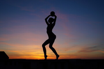 dancer in the dance does the splits in the air against the sunset