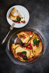Delicious curd casserole with fresh currants and grapes and croutons in a glass baking dish, flat lay