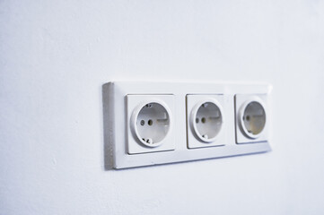 modern electrical sockets on a white wall. Close-up of a triple rosette.