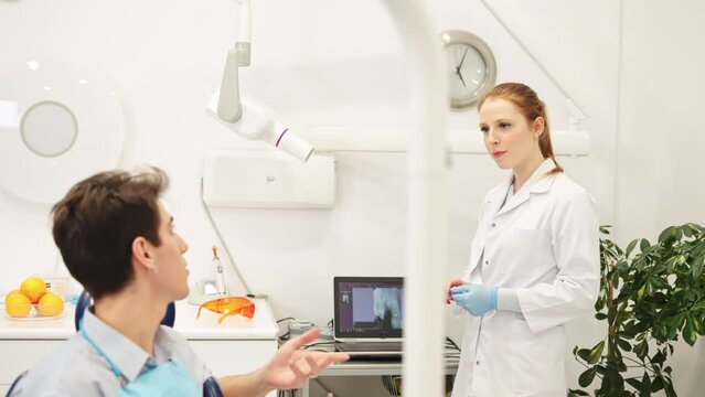 Dentistry consultation. Female dentist discussing dental x-ray with male patient during checkup