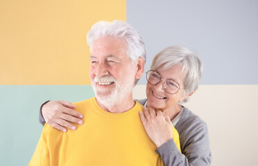 70 years old cute caucasian senior couple standing over isolated colorful background hugging smiling. Portrait of happy lovely white-haired family