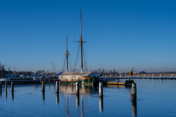Obraz premium A sailboat in a marina closed down for winter. Blue water and a clear blue sky