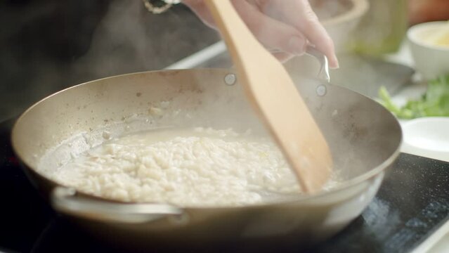 Unrecognizable cook preparing risotto in pan