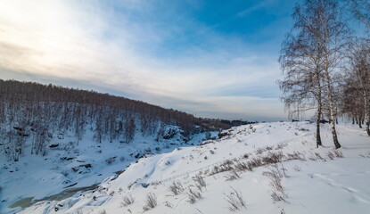 Winter landscape with trees and sky from the high rocky river bank