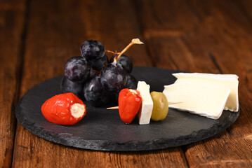 Stuffed cherry peppers with cream cheese and olives on a skewer on the slate board.
