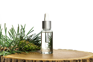 A cosmetic transparent jar with a pipette is filled with oil and pine plant extract on a cut tree. White background. Place for inscriptions and text.