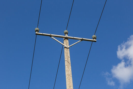 AN OLD FASHIONED WOODEN ELECTRIC POLE WITH WIRES