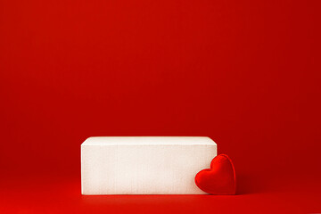 White square podium with red hearts on a red background. Advertising and product presentation. Valentine's Day and 14 February. Mockup for cosmetics.