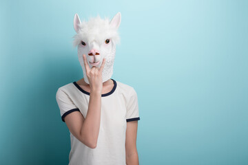 Woman in alpaca mask with hand in rock sign, isolated on blue background