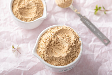 Maca powder in measuring cups and a spoon