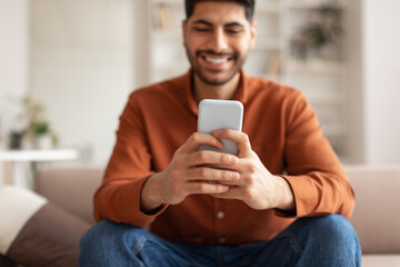 Smiling Arab man using smartphone at home
