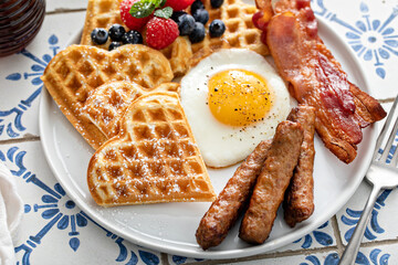 Breakfast table with waffles. fried egg, bacon and sausage