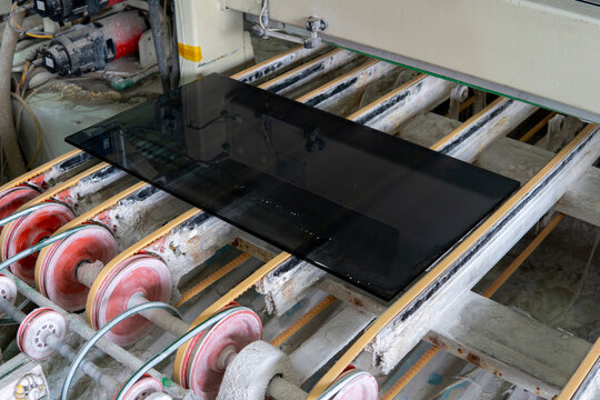 Glass processing and polishing. Dark glass on the conveyor of a glass polishing machine.