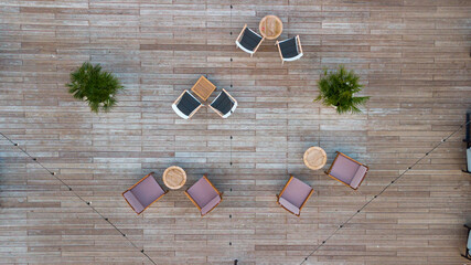 Drone view of open-air terrace with chairs and tables during sunlight