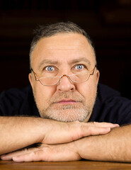 Close-up portrait of a European man with glasses looking into the camera. An interesting adult man posing indoors. Soft focus .