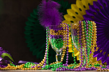 Mardi gras carnivale mask, green, purple, yellow beads on rustic tile background