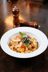 Pasta with tomatoes served on restaurant table. Traditional Italian dish.