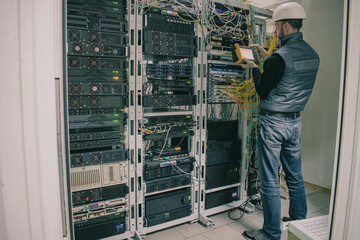 Diagnosing problems with telecommunications equipment. A technician works in a server room in a...