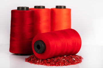Red thread standing on decorative stones in an isolated setting. yarn standing in front of bobbin...