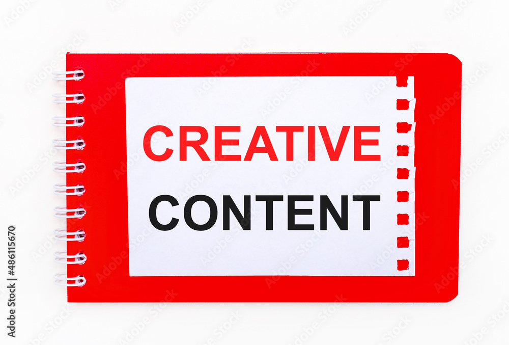 Poster on a white background - a bright red notebook on a spiral. on it is a white sheet of paper with the 