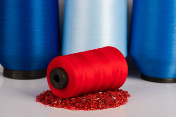 Red thread standing on decorative stones in an isolated setting. yarn standing in front of bobbin...