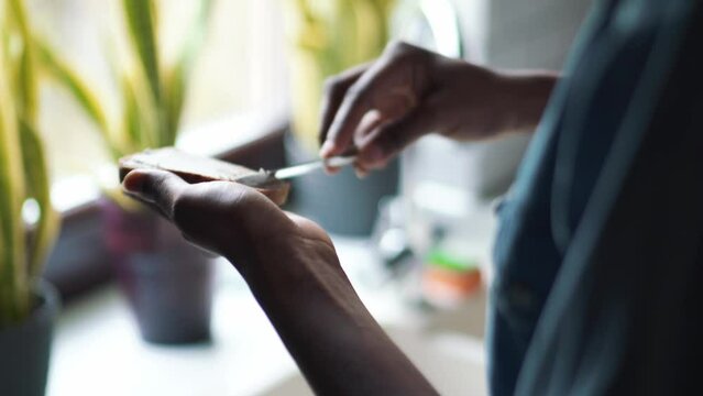 Female hands spread butter on bread in the kitchen