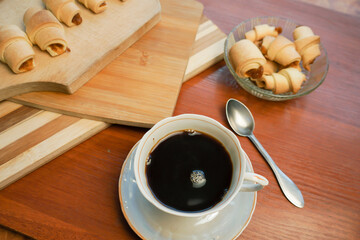 Croissants with apple jam and a cup of coffee on a wooden background.