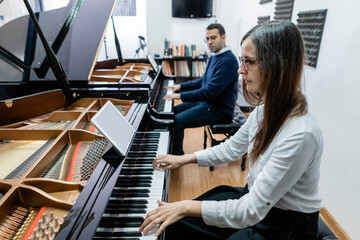 Man and woman playing piano during music lesson