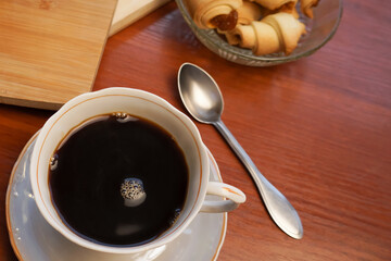 Croissants with apple jam and a cup of coffee on a wooden background.