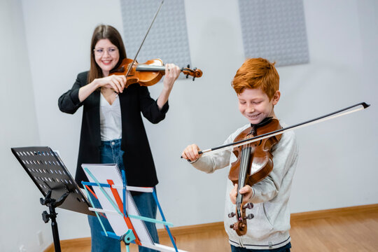 Happy music teacher and child playing violins together