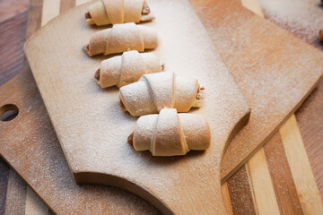 Croissants with apple jam sprinkled with powdered sugar on a wooden background.