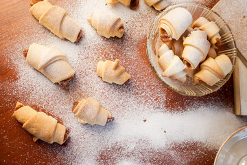 Croissants with apple jam sprinkled with powdered sugar on a wooden background.