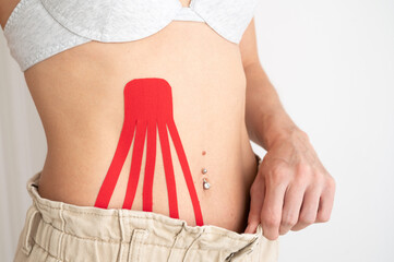 Close-up of sexy body with kinesio tape on the abdomen of young girl. Weight loss concept