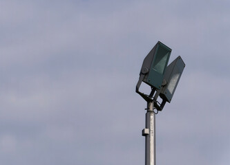 Close-up of a light pole with two lamps with a cloudy sky in the background