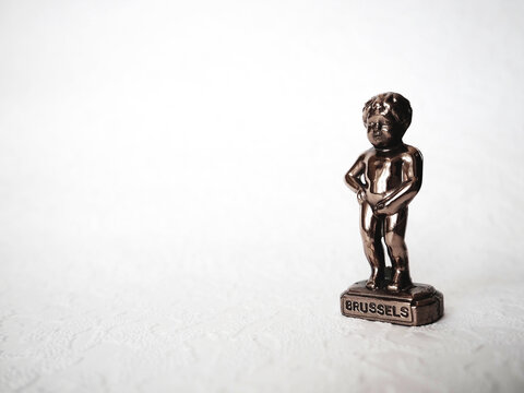Manneken Pis statue on white background. Brussels symbol. Miniature bronze figurine of a naked boy urinating into a pool. Metal souvenir. Baby pissing