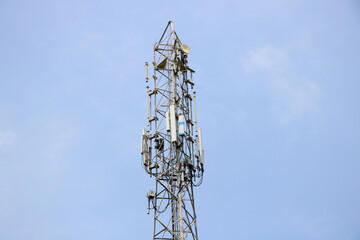 Telecommunication towers with TV antennas and satellite dish on clear blue sky