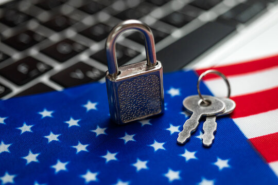 USA cyber security concept. Padlock on computer keyboard and American flag. Close-up view photo