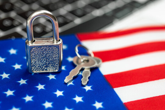 USA cyber security concept. Padlock on computer keyboard and American flag. Close-up view photo