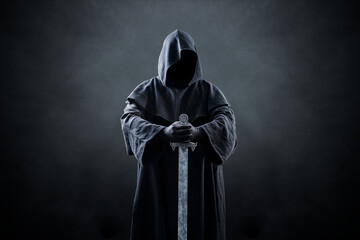 Warrior with hooded cape and medieval sword over dark misty background