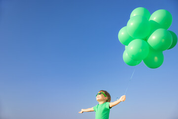 Obraz na płótnie Canvas Happy child with green balloons outdoor