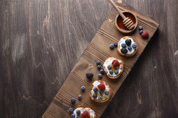 Home breakfast toasts with goat cheese and berries jam on the wooden table. Horizontal top view. Copy space