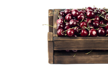 Cherries in box. Sweet fresh cherries in wooden brown box on white background. Close up image with copy space.